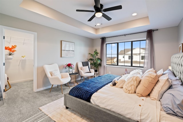 bedroom featuring ceiling fan, light carpet, a closet, and a tray ceiling