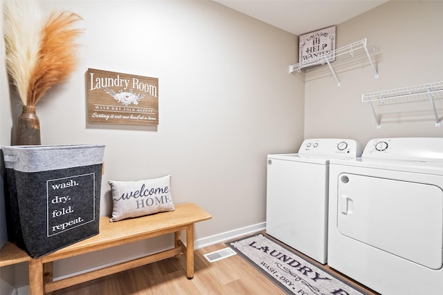 clothes washing area featuring hardwood / wood-style floors and washing machine and clothes dryer