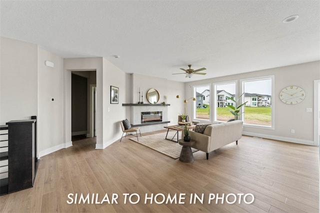 living room featuring ceiling fan, light hardwood / wood-style floors, and a textured ceiling