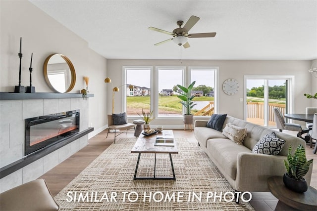 living room featuring a fireplace, ceiling fan, plenty of natural light, and wood-type flooring