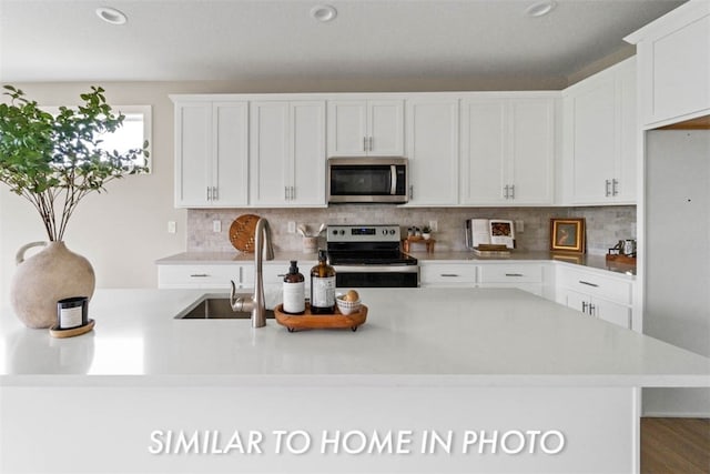 kitchen with appliances with stainless steel finishes, backsplash, white cabinetry, and sink