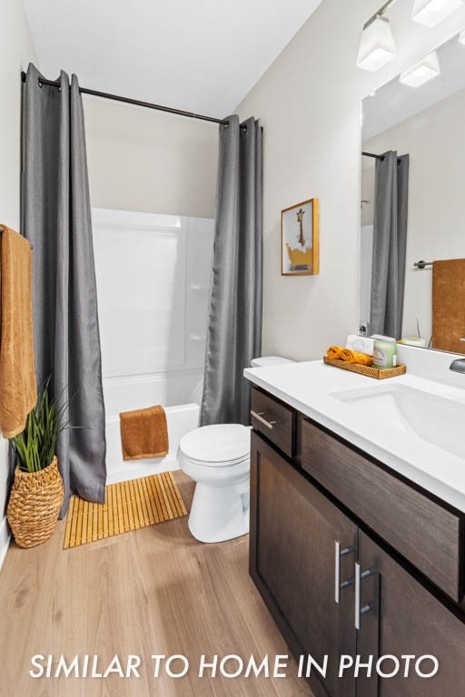 full bathroom featuring hardwood / wood-style floors, vanity, toilet, and shower / tub combo with curtain