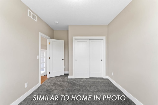 unfurnished bedroom featuring dark colored carpet and a closet