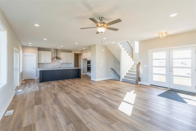 unfurnished living room featuring french doors, sink, light wood-type flooring, and ceiling fan