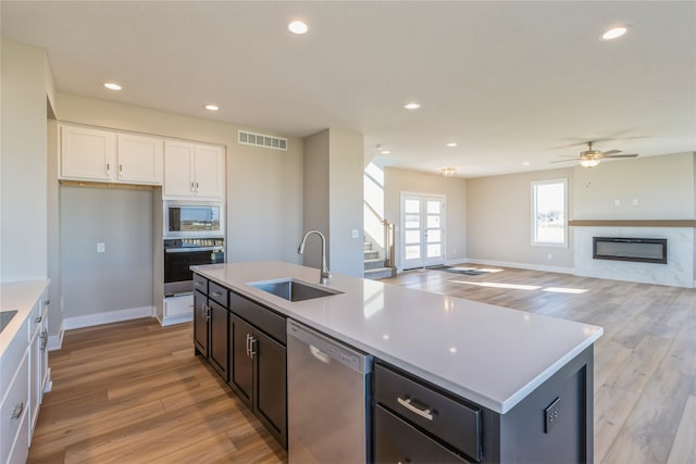 kitchen featuring sink, white cabinetry, light hardwood / wood-style floors, stainless steel appliances, and a kitchen island with sink