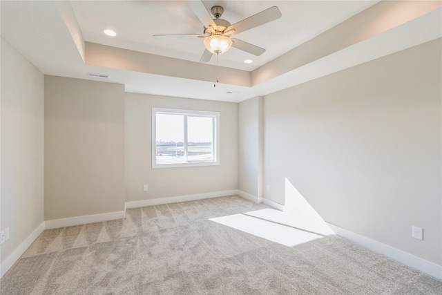 spare room with light carpet, a raised ceiling, and ceiling fan