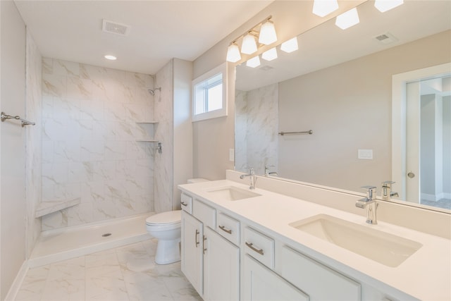 bathroom with a tile shower, toilet, and vanity