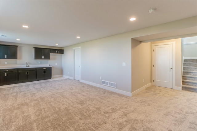 unfurnished living room with sink and light colored carpet