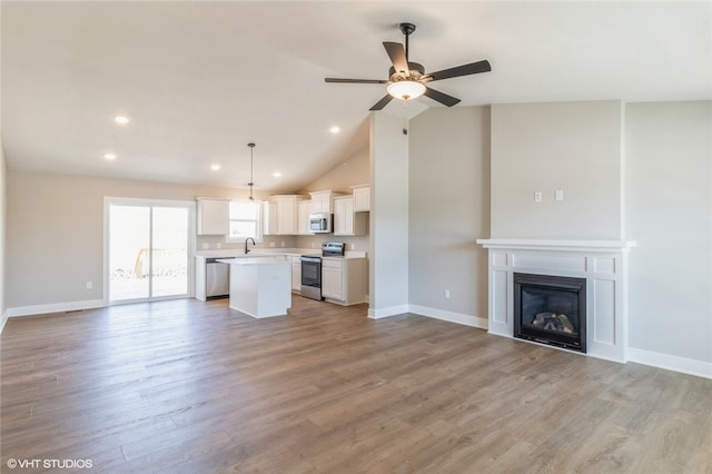 kitchen with a kitchen island, white cabinetry, light hardwood / wood-style flooring, decorative light fixtures, and stainless steel appliances