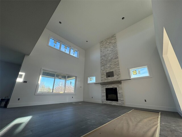 unfurnished living room featuring a fireplace, high vaulted ceiling, and dark wood-type flooring