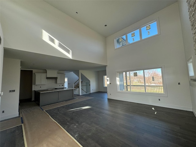 unfurnished living room featuring dark hardwood / wood-style flooring and a high ceiling