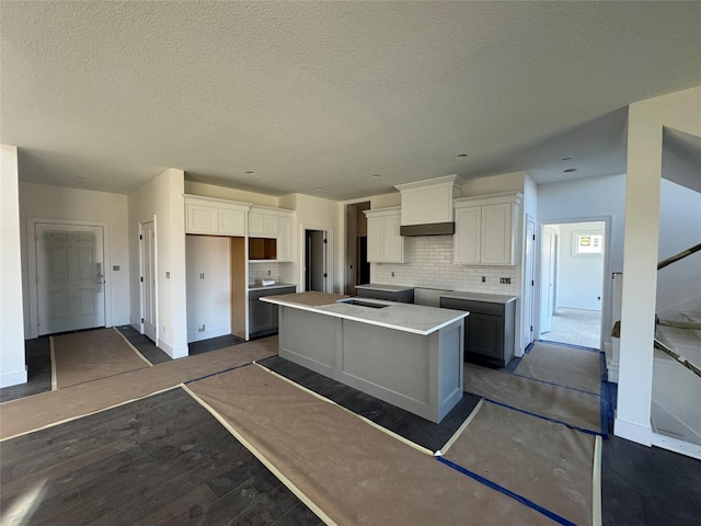 kitchen with white cabinetry, decorative backsplash, a kitchen island, and a textured ceiling