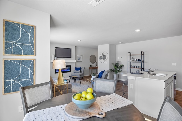 dining space with wine cooler, visible vents, a glass covered fireplace, wood finished floors, and baseboards