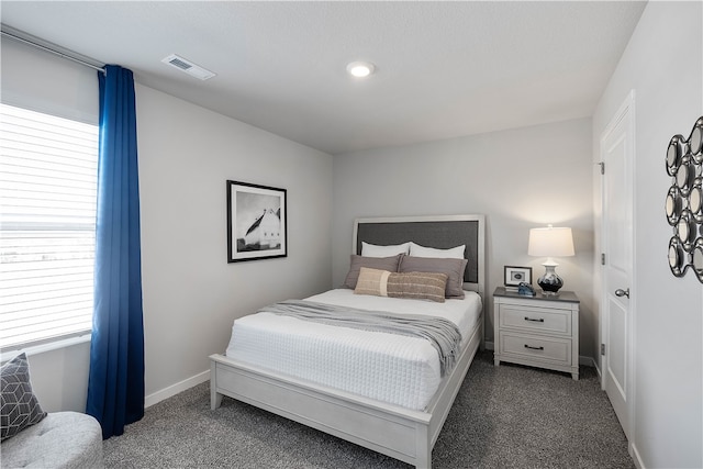 bedroom featuring dark carpet, visible vents, and baseboards