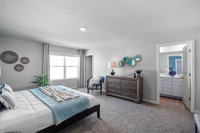 carpeted bedroom with connected bathroom and a textured ceiling