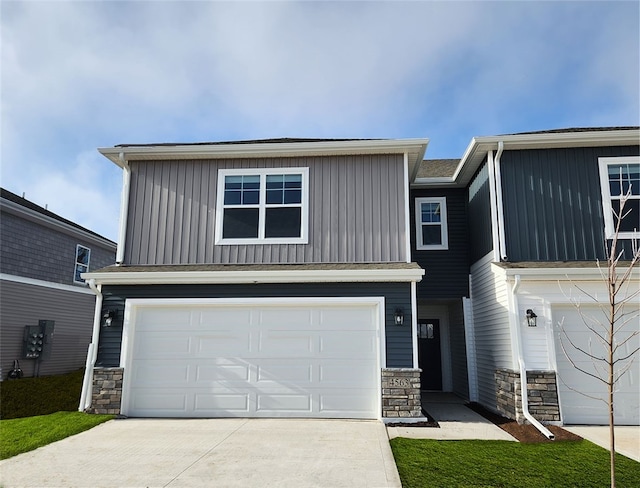 view of front of house featuring a garage, stone siding, board and batten siding, and concrete driveway