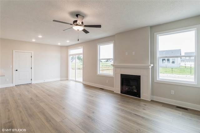 unfurnished living room with light wood-type flooring, ceiling fan, and a textured ceiling