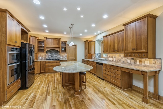 kitchen with a kitchen island, a kitchen breakfast bar, light hardwood / wood-style flooring, decorative light fixtures, and appliances with stainless steel finishes