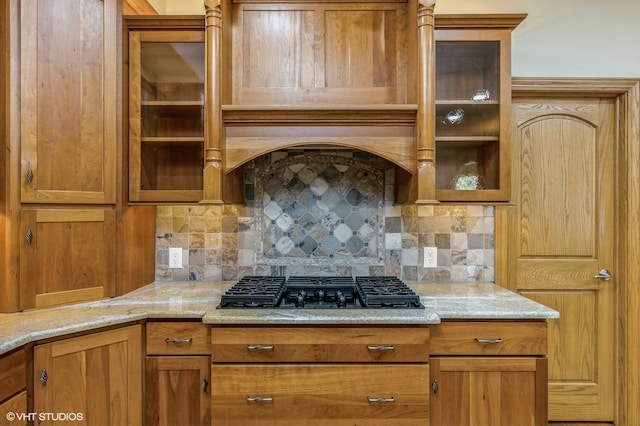 kitchen featuring decorative backsplash, gas cooktop, and light stone counters