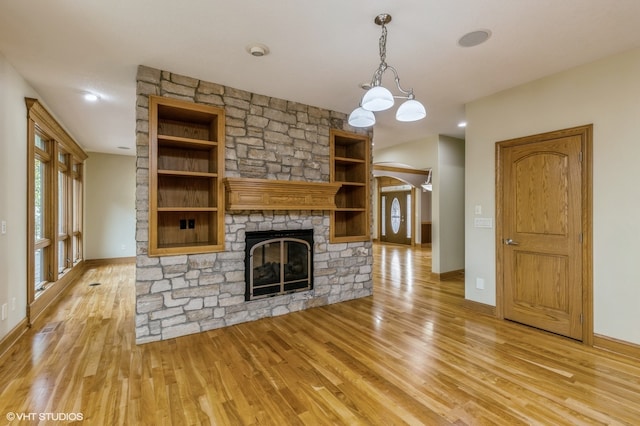 unfurnished living room with light hardwood / wood-style floors and a stone fireplace