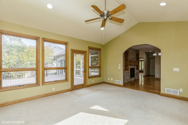 unfurnished living room with ceiling fan, a stone fireplace, carpet flooring, and lofted ceiling