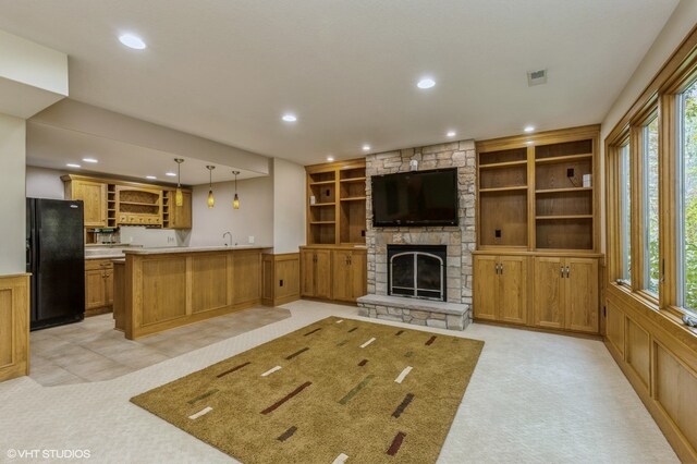 unfurnished living room featuring a stone fireplace, light carpet, and a healthy amount of sunlight