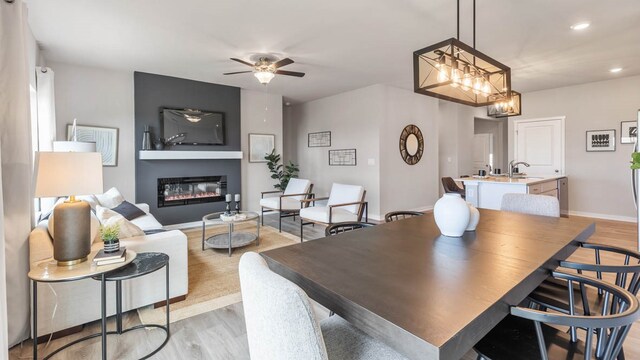 dining area featuring ceiling fan with notable chandelier and light hardwood / wood-style floors