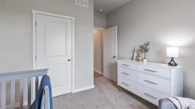 bedroom with light carpet and a nursery area