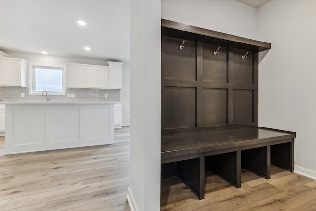 mudroom with sink and light hardwood / wood-style flooring