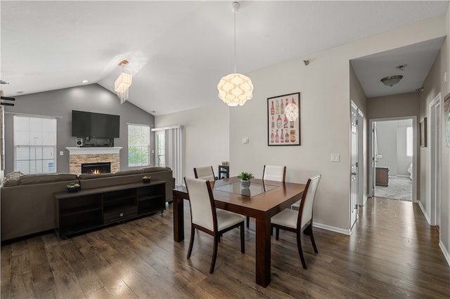 dining space with dark hardwood / wood-style flooring, lofted ceiling, and a fireplace