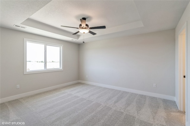 unfurnished room with light carpet, a raised ceiling, and ceiling fan