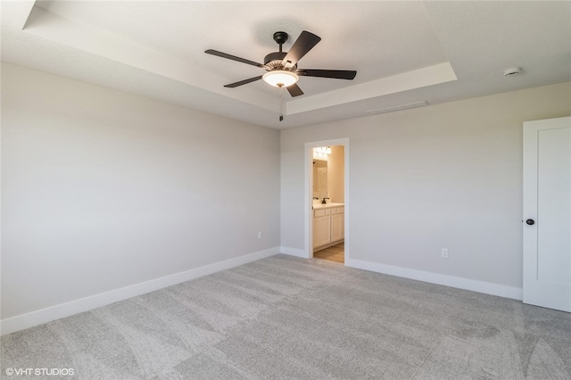 carpeted empty room with a tray ceiling and ceiling fan