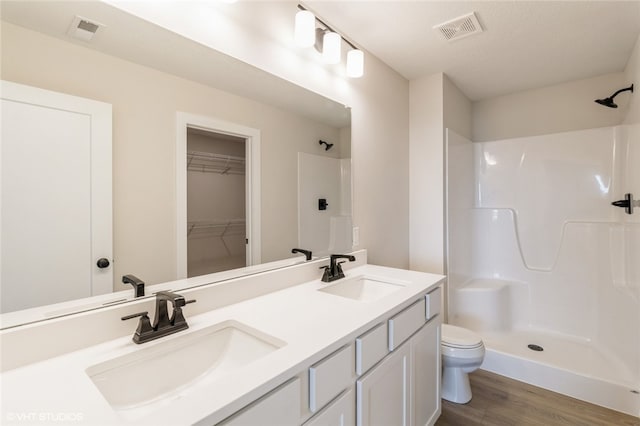 bathroom featuring toilet, vanity, a shower, and wood-type flooring