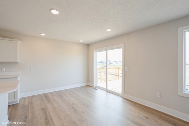 unfurnished living room with a textured ceiling and light wood-type flooring