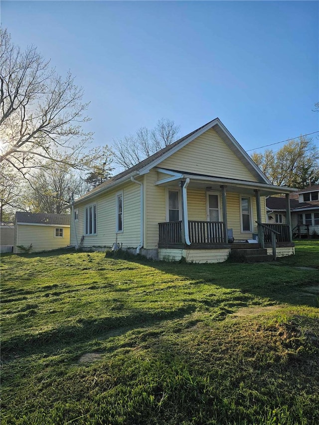 view of home's exterior with covered porch and a lawn