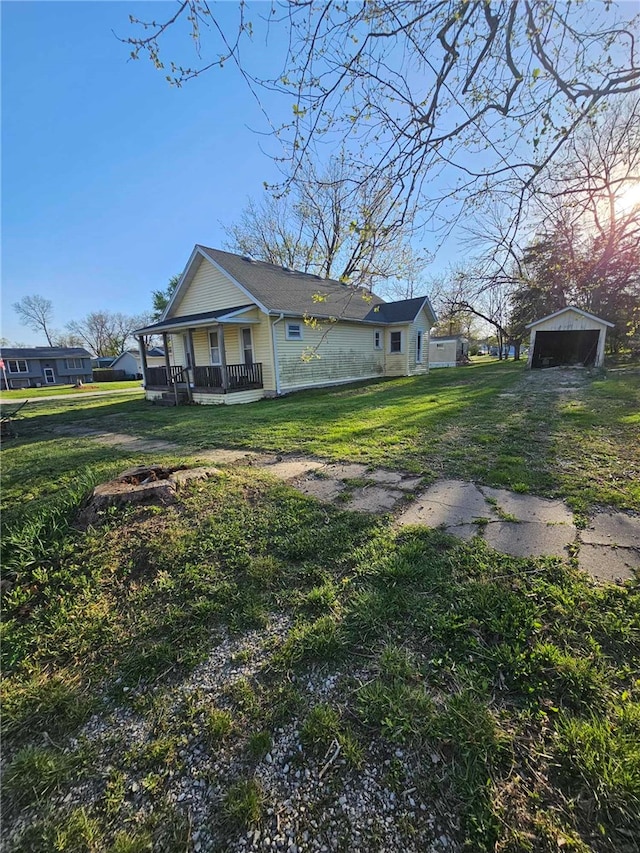 exterior space featuring covered porch, a garage, an outbuilding, and a lawn