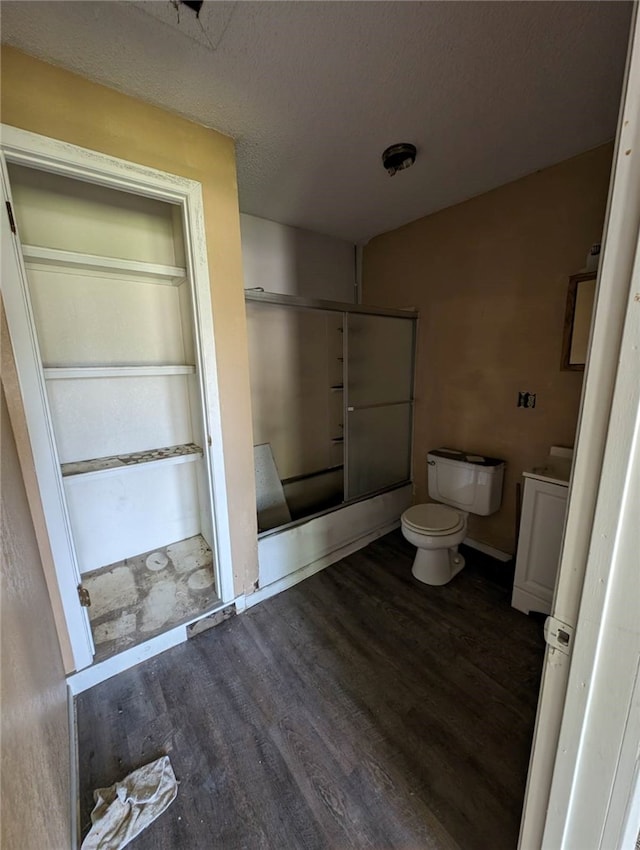 bathroom with walk in shower, wood-type flooring, toilet, and a textured ceiling