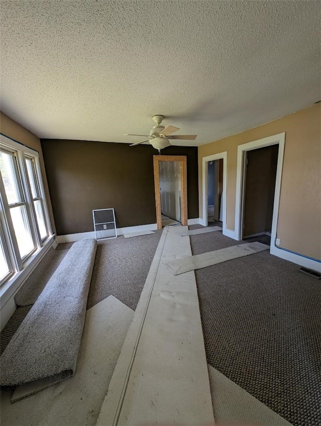 interior space featuring a textured ceiling, ceiling fan, and carpet flooring