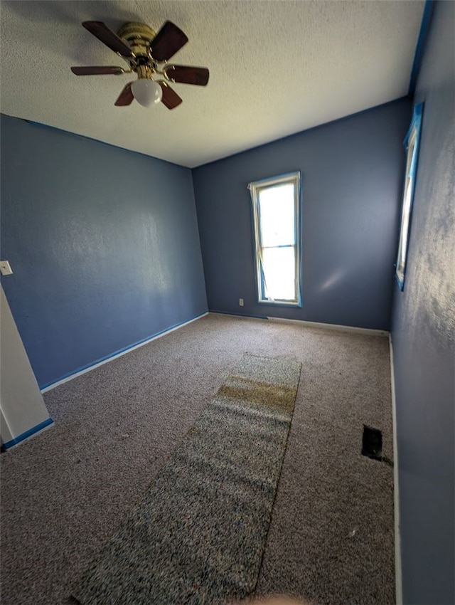 empty room with a textured ceiling, carpet floors, and ceiling fan