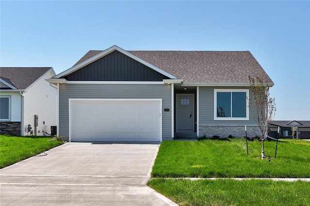 view of front facade with cooling unit, a garage, and a front yard