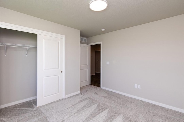 unfurnished bedroom featuring light carpet and a closet