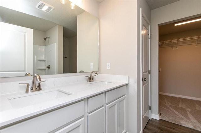 bathroom with hardwood / wood-style flooring, vanity, and walk in shower