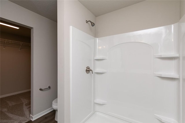 bathroom with a shower, a textured ceiling, and toilet