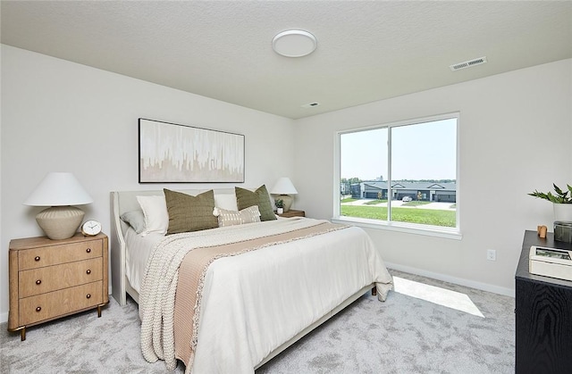 bedroom with a textured ceiling and light colored carpet