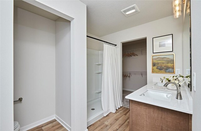 bathroom featuring vanity, curtained shower, a textured ceiling, hardwood / wood-style flooring, and toilet