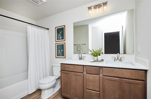 full bathroom with vanity, a textured ceiling, shower / bath combo with shower curtain, hardwood / wood-style flooring, and toilet