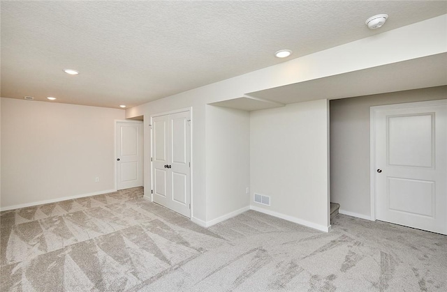 basement featuring light carpet and a textured ceiling