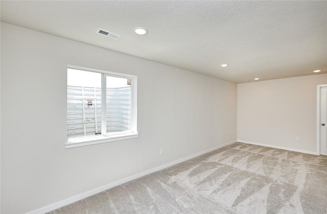 carpeted empty room featuring a textured ceiling