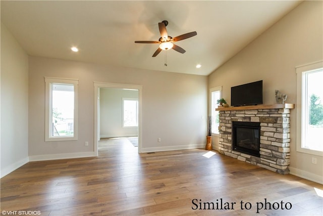 unfurnished living room featuring hardwood / wood-style floors, lofted ceiling, ceiling fan, and a healthy amount of sunlight