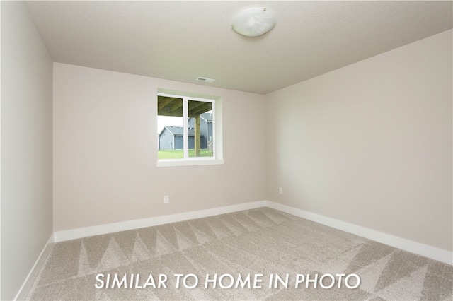 spare room featuring carpet, baseboards, and a textured ceiling